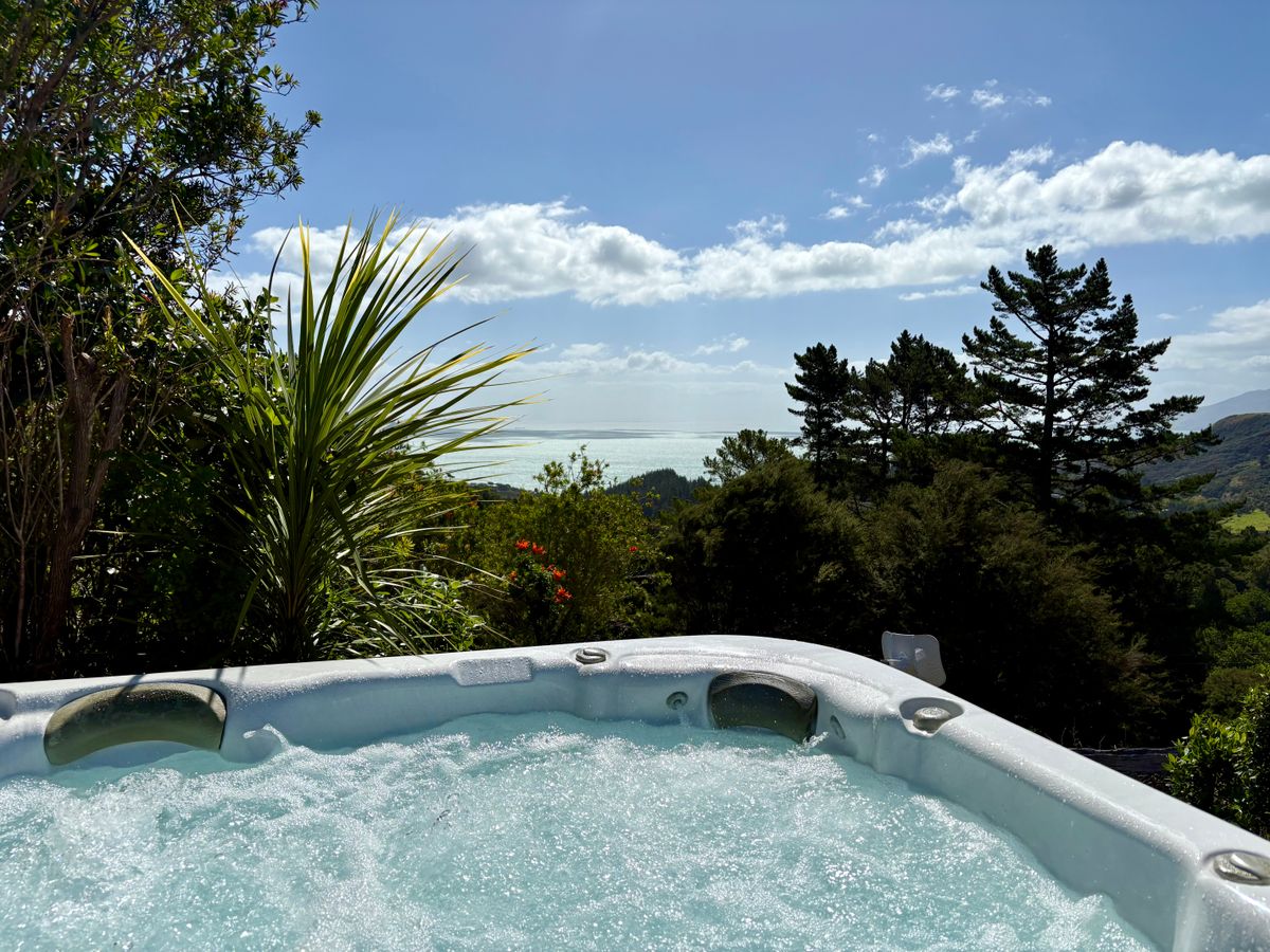 Luxury outdoor spa pool at Whitestar Station's Ocean View Retreat, looking across native bush to the Hauraki Gulf and Northern Coromandel coastline.